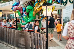 Eine Frau die mit Ballons im Biergarten auf dem Rosenheimer Herbstfest steht und die Kamera lächelt