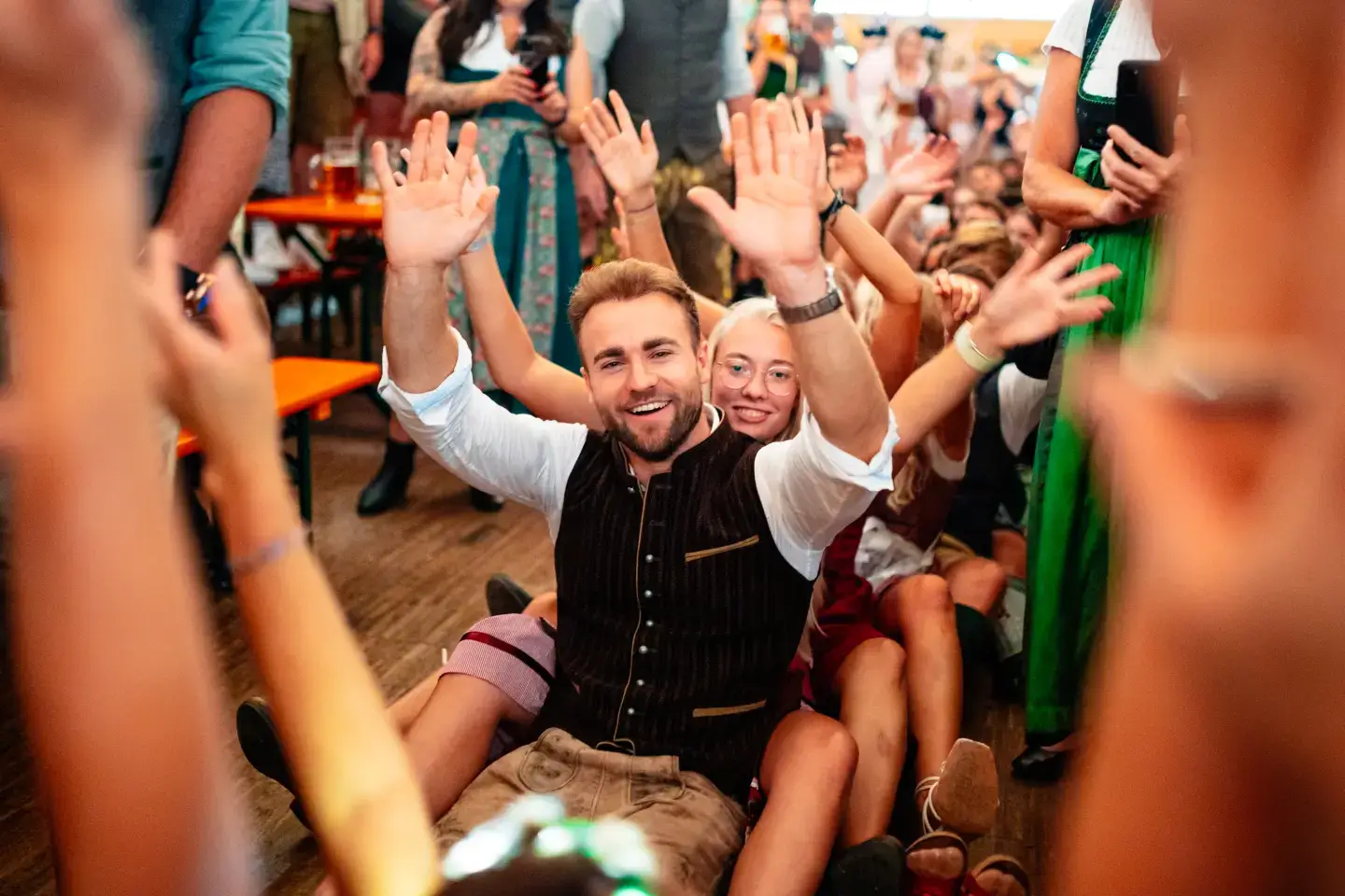 Besucher die auf dem Rosenheimer Herbstfest eine Sitz-Polonaise machen und dabei die Arme hochheben