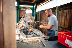 Ein Mann der an einem Grill Fisch zubereitet auf dem Rosenheimer Herbstfest