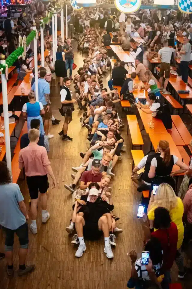 Besucher des Rosenheimer Herbstfestes die in einer Reihe hintereinander sitzen